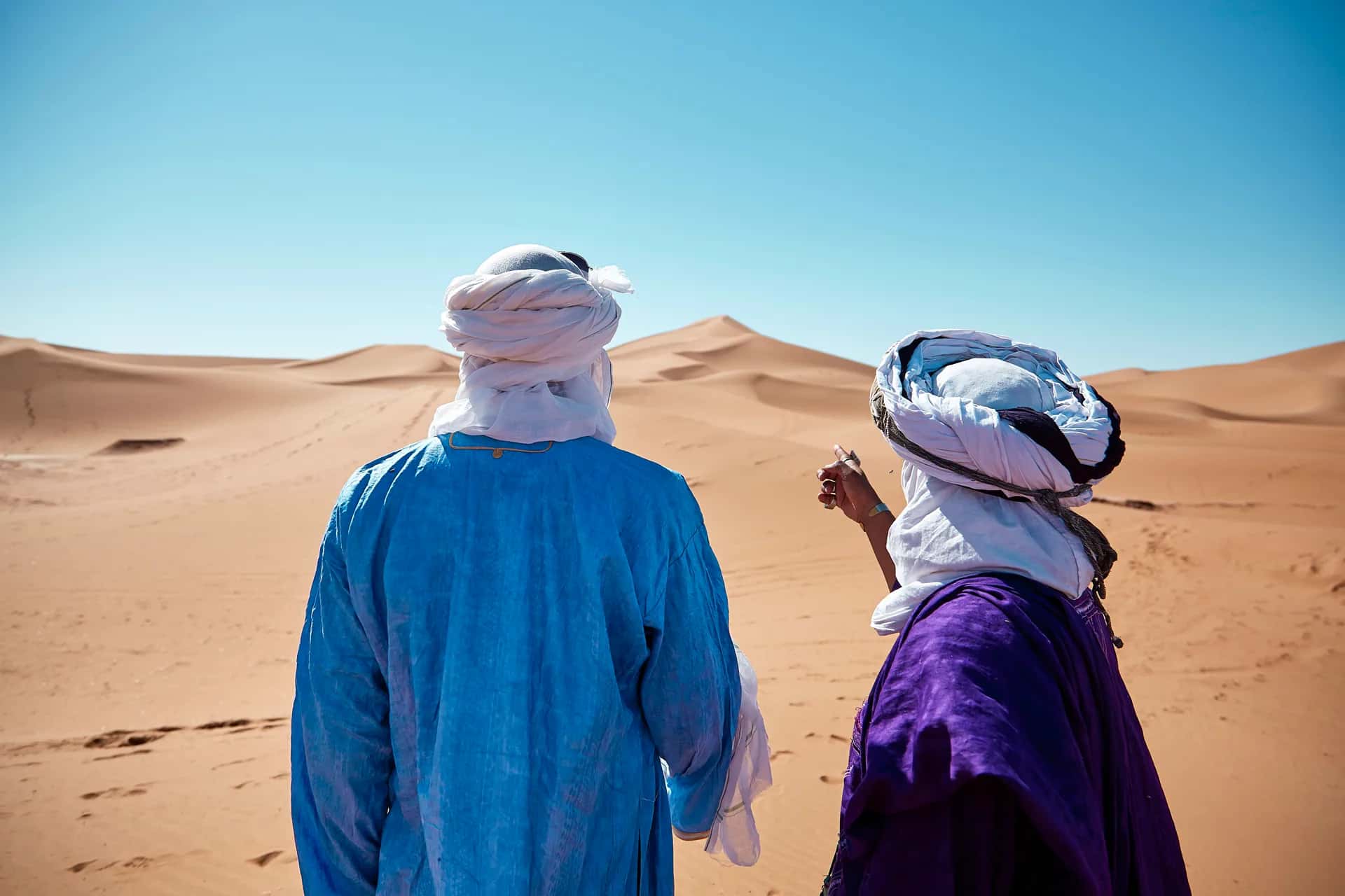 Two guides in traditional dress on the dunes