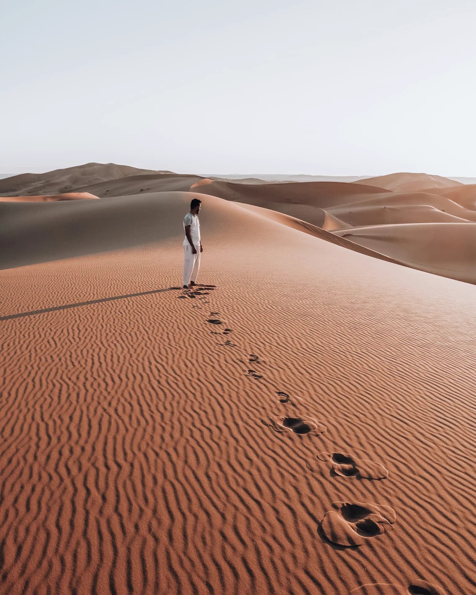 Footprints climbing a dune ridge