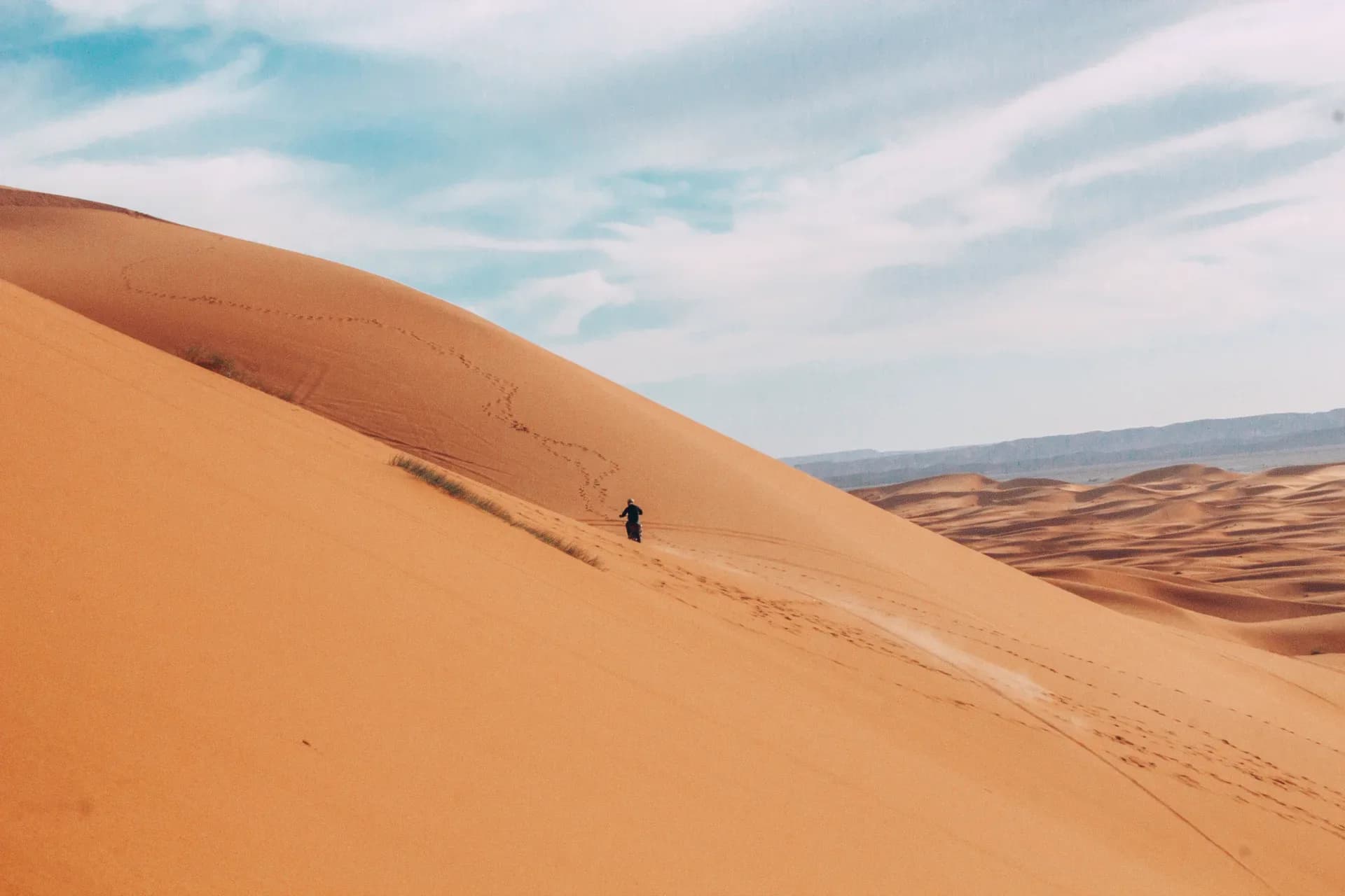 A rider crossing the ridge of a great dune at Erg Chebbi